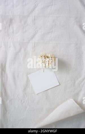 Carta bianca e fiore bianco su tessuto bianco, sfondo decorativo Foto Stock