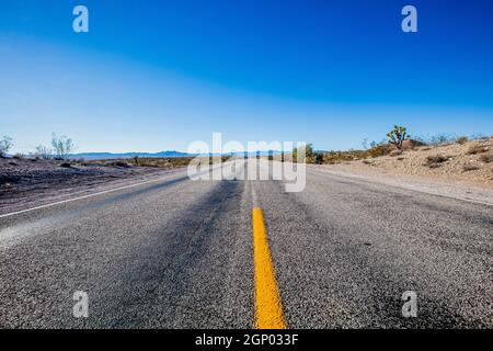 Strada senza fine attraverso il deserto fotografata vicino a Primm sul confine tra il Nevada, la California e l'Arizona Foto Stock