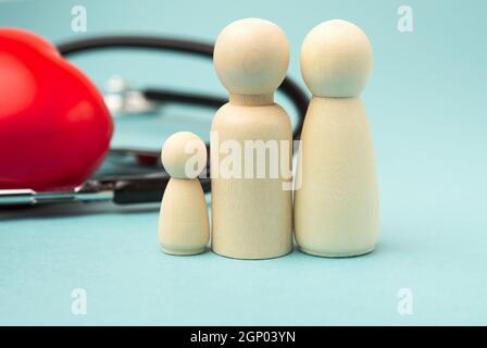 famiglia di figure in legno di uomini sullo sfondo di cuore rosso e stetoscopio, concetto di assicurazione sanitaria, primo piano Foto Stock