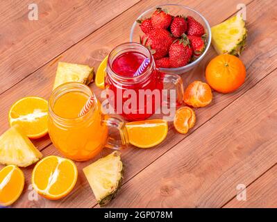 Fragole fresche e arancione con cocktailes frutti su un rustico in legno sfondo. Appena miscelato frullato estivo bello bere durante una giornata calda. Foto Stock