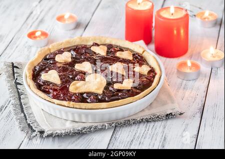 San Valentino marmellata di ciliegie crostata con candele brucianti Foto Stock