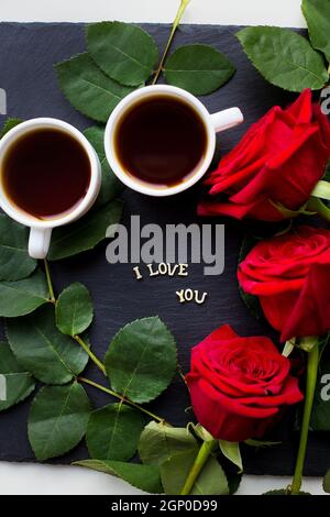 L'iscrizione ti amo su sfondo nero, caffè, rose rosse, primo piano Foto Stock