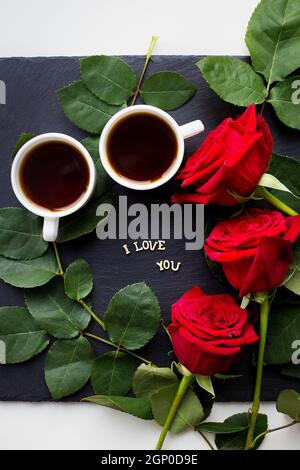 L'iscrizione ti amo su sfondo nero, caffè, rose rosse, primo piano Foto Stock