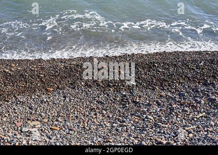 Piccole rocce spiaggia, sfondo non focalizzato, nessuno, in primo piano, soleggiato, grandi e piccole pietre Foto Stock