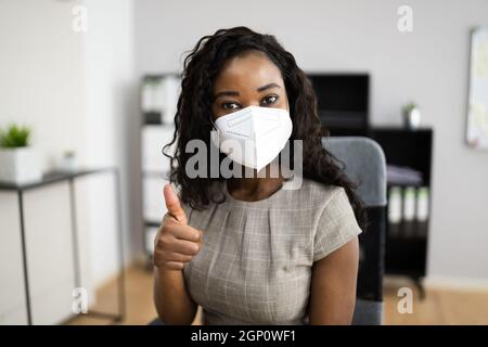 Donna Africana americana alla reception dell'ufficio in FFP2 maschera facciale Foto Stock