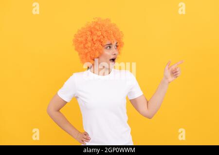 guardate là. stupito aspetto di festa fantasia. donna freaky in clown wig puntando dito, copia spazio Foto Stock