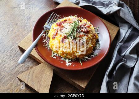 Risotto con zucca e pancetta su un tavolo di legno scuro Foto Stock