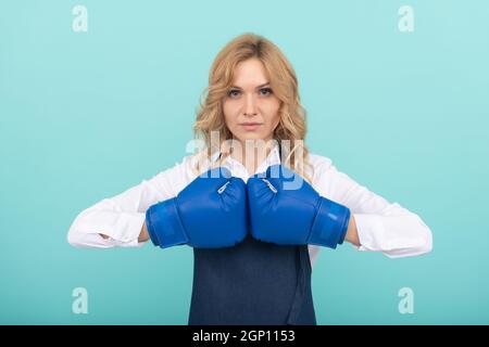 donna in cuoco grembiule che tiene pugni in guanti da boxe, potere Foto Stock