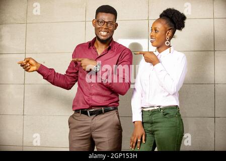 Ritratto di attraente giovane coppia uomo e donna sorridente e puntando le dita a lato Foto Stock