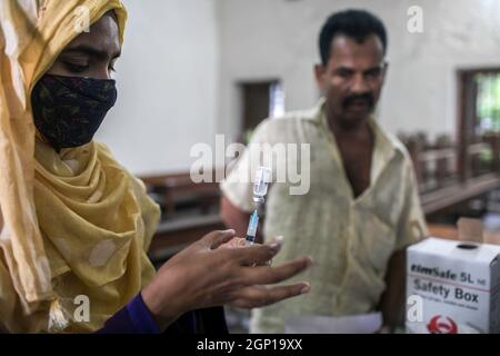 Dhaka, Bangladesh. 28 settembre 2021. Un operatore sanitario si prepara a somministrare una dose di vaccino moderna COVID19 a un uomo durante una campagna di vaccinazione in un centro di vaccinazione a Dhaka. Martedì è iniziata una campagna di vaccinazione di massa a livello nazionale con l'obiettivo di inoculare 7.5 milioni di persone in occasione del compleanno del primo ministro Sheikh Hasina. Credit: SOPA Images Limited/Alamy Live News Foto Stock