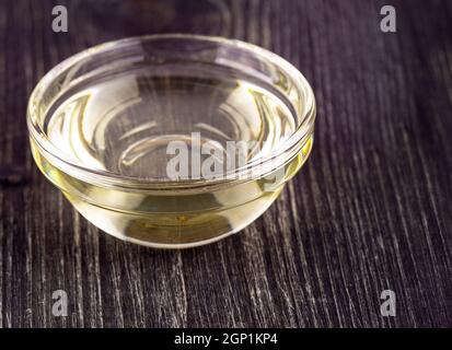Cottura dell'olio vegetale in una piccola tazza di vetro su un vecchio tavolo di legno Foto Stock