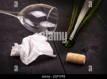 Usato accartocciata bianco tovagliolo di carta e vuota una bottiglia di vino con sughero sul vecchio tavolo in legno Foto Stock