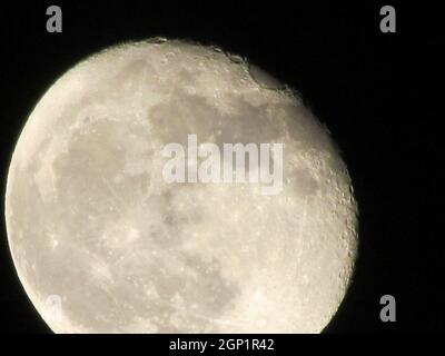 Luna della Terra che si illumina su sfondo nero. La Luna in primo piano su un cielo notturno nero girato attraverso una teleobiettivo fotocamera. Foto Stock