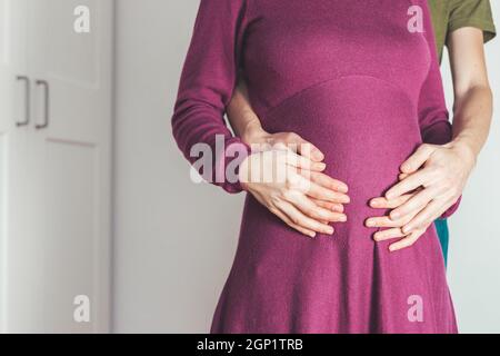 Close up of pregnant mother and father, hugging the tummy, Caucasian Foto Stock