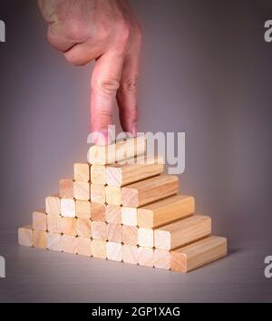 Mano maschio con due dita sulla parte superiore di un piolo di legno su una scala Foto Stock