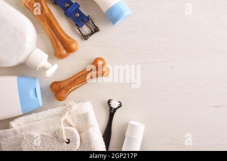 Igiene canina di cappotto, corpo e denti con prodotti su tavola bianca in legno. Vista dall'alto. Composizione orizzontale. Foto Stock