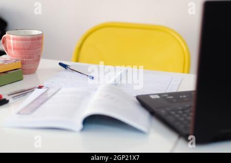 scrivania per studenti con libri, penne e computer. scrivania per uomo d'affari con laptop e materiali da biblioteca. spazio per copie su una parete bianca vuota Foto Stock