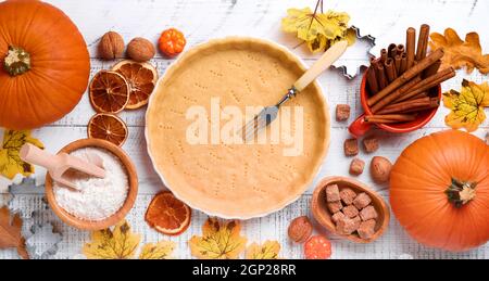 Ingredienti di zucca e cibo, spezie, cannella e utencil da cucina su sfondo bianco rustico in legno. Concetto di cottura fatta in casa per le vacanze. Pentola di cottura Foto Stock