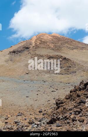 Vista ravvicinata del vulcano Teide con un cielo blu e una nuvola bianca appena sopra la cima Foto Stock