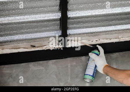 La mano umana nel guanto bianco sta cianfrinando le perdite del tetto con la schiuma di caulk inscatolata. Foto Stock