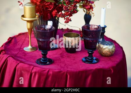 Bicchieri da vino e candelabri sul tavolo rosso. Foto Stock