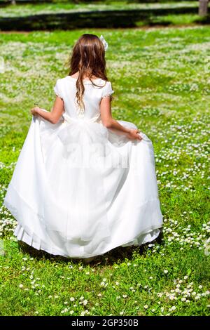 Giovane ragazza in abito bianco che cammina in campo di fiori. Foto Stock