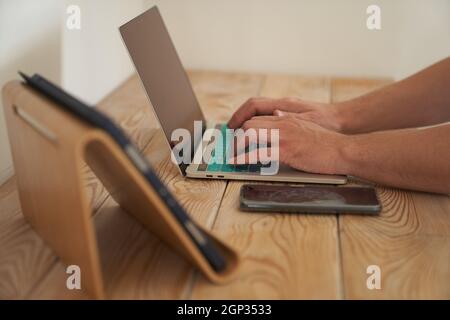 Primo piano delle mani di un uomo che digita su una tastiera, cercando informazioni. Un copywriter freelance sta lavorando ad un progetto. Il concetto di lavoro a distanza. Foto di alta qualità Foto Stock