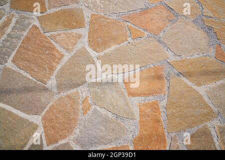 Superficie stradale arancione in pietra. Trama senza giunture. La tessitura di una strada di pietra. Foto di alta qualità Foto Stock