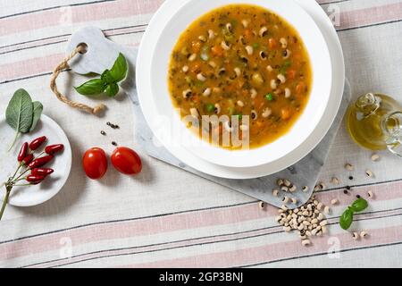 Minestrone italiano con verdure e fagioli su un tavolo con tovaglia di lino Foto Stock
