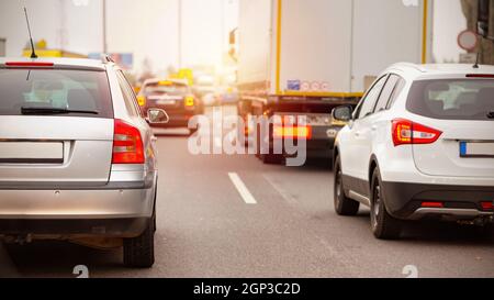 Line od auto in attesa di traffico jam in ore di punta. Automobili con luci di stop su stucked su autostrada in una città. Veicoli che viaggiano su strade affollate. Foto Stock