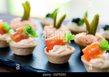 Macro primo piano di mini tartine di pasta sfoglia con salmone affumicato, granchio cremoso e ripieno salato. Foto Stock