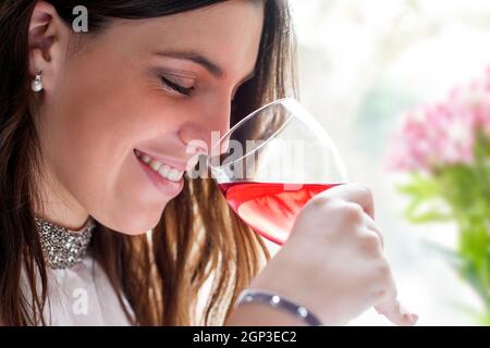 Primo piano immagine del viso di un attraente vino brunette odore con gli occhi chiusi. Foto Stock
