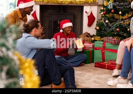 Felice diversi amici maschili e femminili condividere i regali a natale Foto Stock