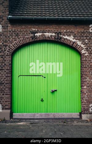 Verde brillante delle grandi porte di legno in un vecchio edificio in mattoni. Le porte di un edificio ristrutturato. Foto Stock