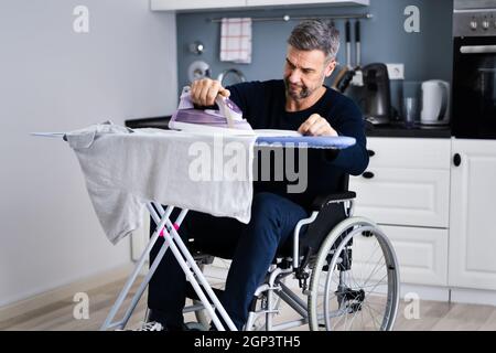 Uomo disabili in abiti da stiro per sedie a rotelle Foto Stock