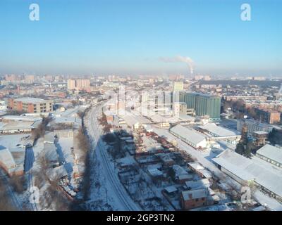 Città d'inverno. Frosty giornata soleggiata nella città. La neve sulle strade e il fumo dalla caldaia aumenta. Il gelo e il sole, una splendida giornata. Foto Stock