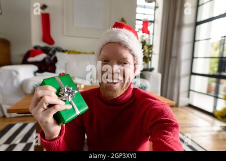 Albino african american uomo che indossa santa Hat fare videochiamata con decorazioni di natale Foto Stock