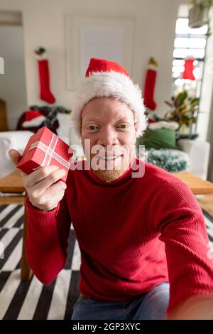 Albino african american uomo che indossa santa Hat fare videochiamata con decorazioni di natale Foto Stock