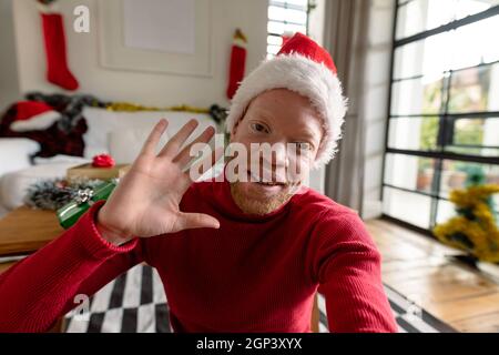 Albino african american uomo che indossa santa Hat fare videochiamata con decorazioni di natale Foto Stock