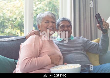 Due diverse coppie anziane sedute sul divano, guardando la tv e divertendosi Foto Stock