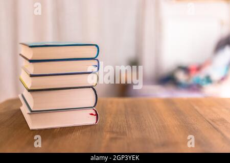 Pila di libri che giace sulla scrivania in legno a casa. La conoscenza e la scienza Foto Stock