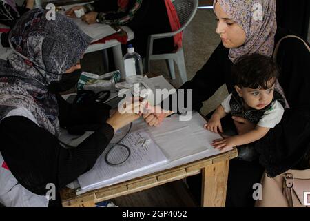 Città di Gaza, Città di Gaza. 28 settembre 2021. Un operatore medico fornisce assistenza medica gratuita a una donna nel quartiere di al-Shejaiya, Gaza City, il 28 settembre 2021. Per molte ore al giorno, un paio di cliniche mediche mobili si spostano da un'area povera e remota a un'altra per fornire servizi sanitari e cure ai residenti bisognosi. PER ANDARE CON 'Feature: Ambulatori mobili fornire servizi sanitari in aree impoverite e remote di Gaza' credito: Rizek Abdeljawad/Xinhua/Alamy Live News Foto Stock