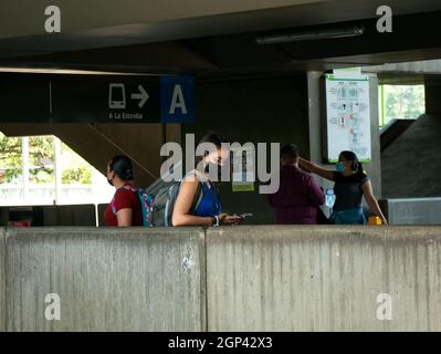 Medellin, Antioquia, Colombia - Settembre 12 2021: La donna indossa una maschera nera protettiva mentre usa il suo telefono e aspetta in una stazione della metropolitana Foto Stock