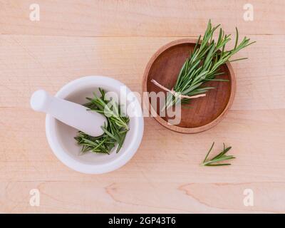 Rosmarino fresco medicina di erbe in un mortaio e ciotola di legno sul tavolo di legno Foto Stock