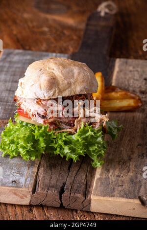 carne di maiale tirata in un panino con patatine fritte Foto Stock