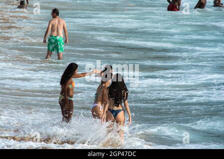 Salvador, Bahia, Brasile - 08 gennaio 2019: Persone alla spiaggia di Porto da barra che entra nel mare di intense onde. Foto Stock