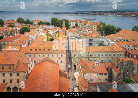 Vista a volo d'uccello o drone sui tetti di tegole arancioni e stretti vicoli in pietra della città vecchia di Zara. Baia e costa del Mare Adriatico, Croazia Foto Stock