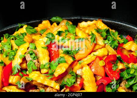 Patate fritte con verdure e funghi in una padella nera. Concetto - alimento grasso, problema di obesità. Foto Stock