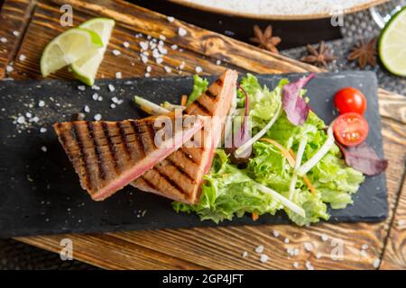 Filetto di pesce alla griglia con spezie e salse. Verdure grigliate, contorno. Concetto - cibo, prelibatezze. Foto Stock