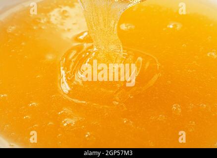 Close up sullo sfondo di un fresco di versamento denso liquido miele di acacia nel recipiente, ad alto angolo di visione Foto Stock